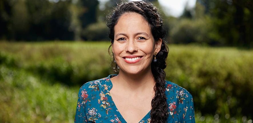 Researcher Natalia stands in a beautiful green landscape