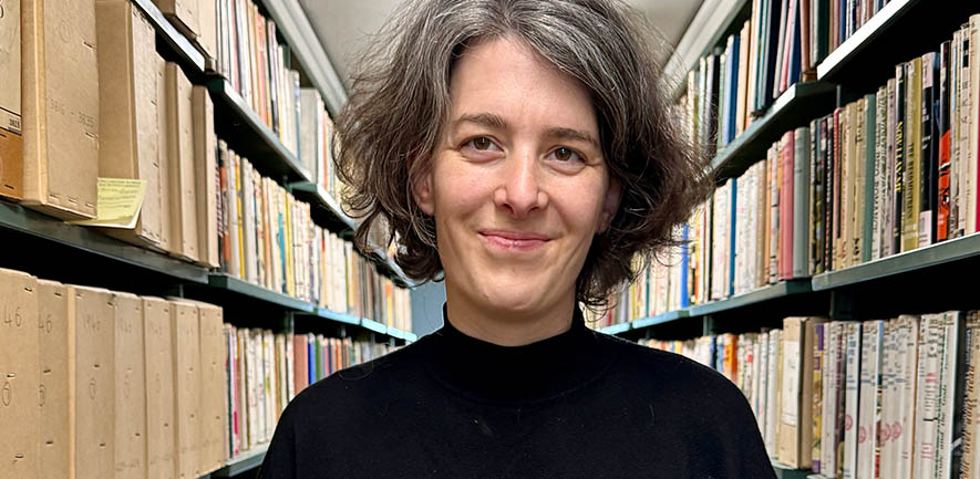 Researcher Sarah stands in a library