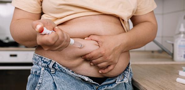 Obese woman injecting weight-loss drug into abdomen