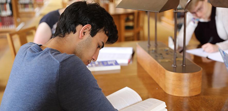 Student at a desk reading a book