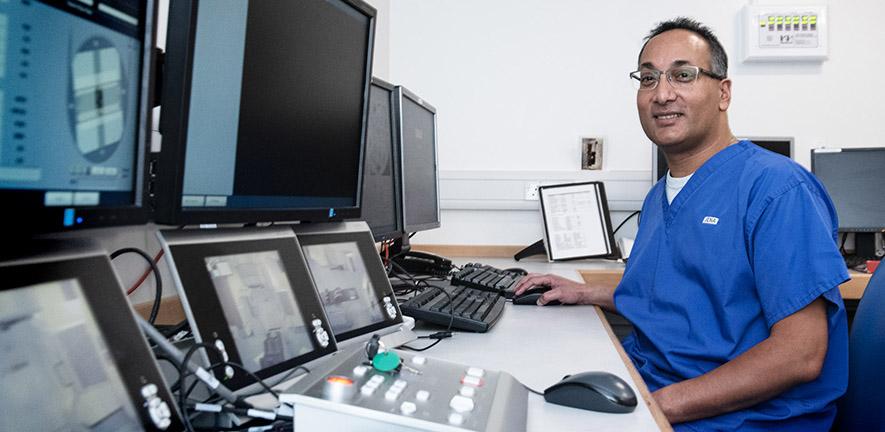 Dr Raj Jena in front of a computer