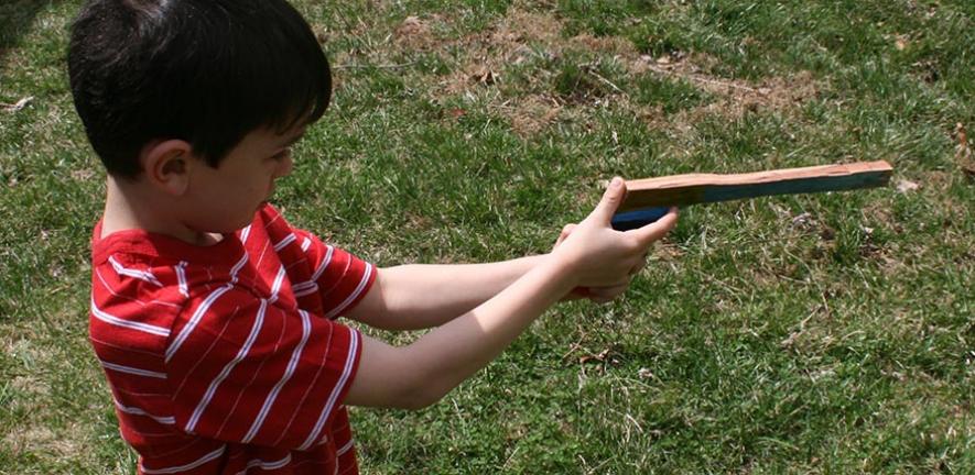 Boy playing with a toy gun made of wood