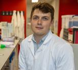 Cancer researcher Tom Else sitting in a lab wearing a white lab coat