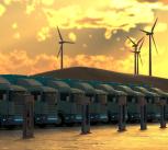 A row of clean energy trucks, wind turbines in the background