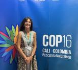 Melissa Leach stands in front of COP16 banner