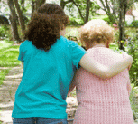 Granddaughter helping her disabled grandmother walk with the aid of a walker.