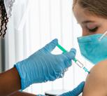 Young girl watching herself being injected with COVID-19 vaccine at a medical clinic