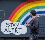 Man walking past Stay Alert/Save Lives artwork