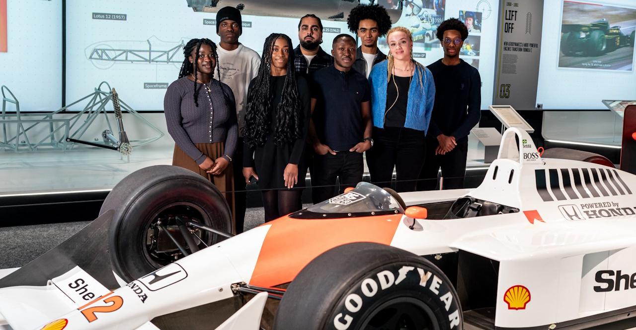 Masters in Motorsports scholars standing behind a Formula 1 car. Photo courtesy of Mission 44