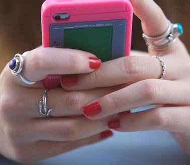 Young woman holding pink mobile phone. Photo by Getty Images