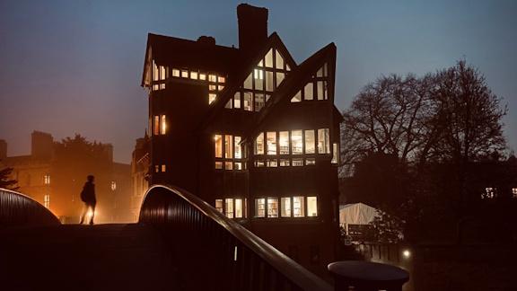 The Jerwood Library of Trinity Hall, built next to Garret Hostel Bridge at night with one person standing on the bridge