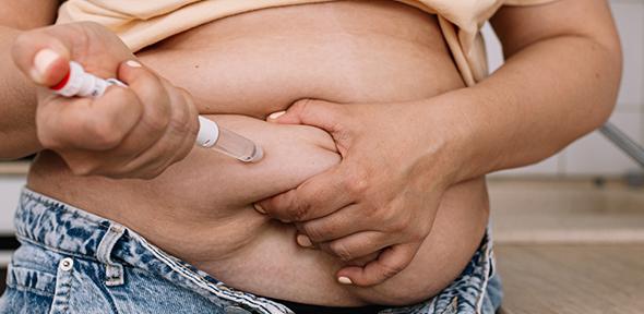 Obese woman injecting weight-loss drug into abdomen