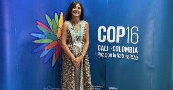 Melissa Leach stands in front of COP16 banner