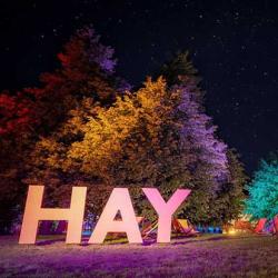 View of large letters spelling out HAY and a tent with deck chairs in the background. 