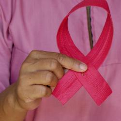 Woman holds pink breast cancer awareness ribbon. 