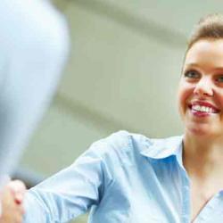 Happy young business woman shaking hands with another female