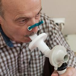 Man testing breathing function by spirometry - stock photo