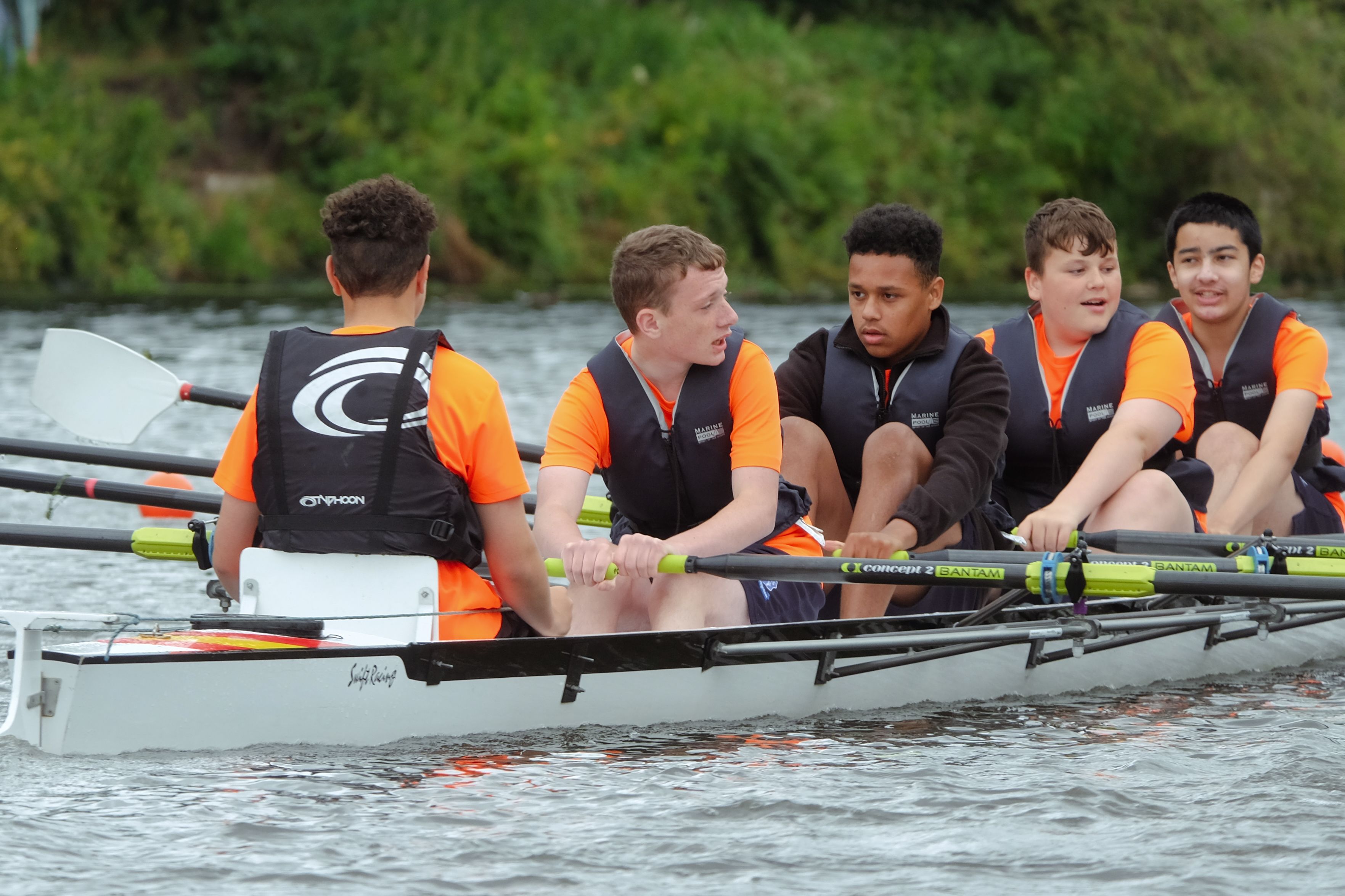 Five boys on the water in a rowing boat