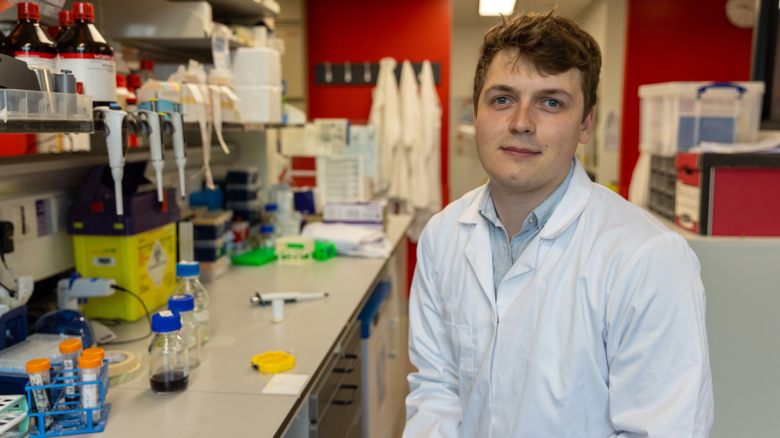 Tom Else sitting at a lab bench wearing a white lab coat