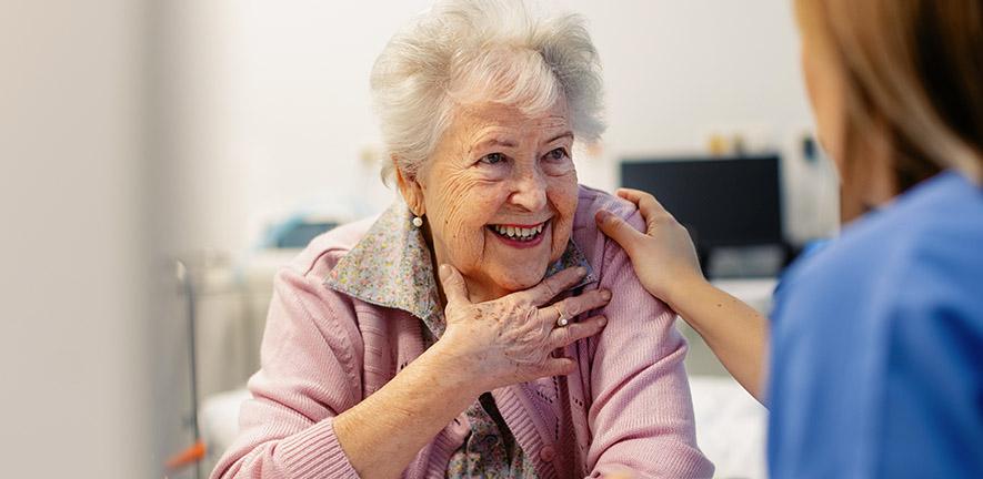 Smiling elderly woman speaking to a healthcare worker