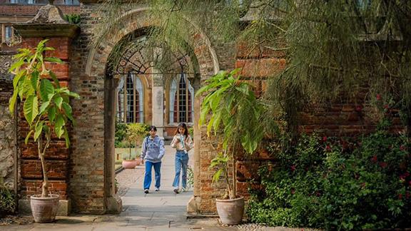 Two students walking through an archway at Pembroke College, Cambridge.