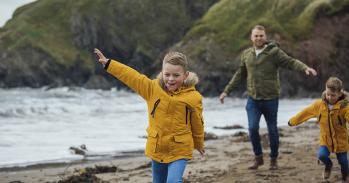 A father and two sons running on a beach