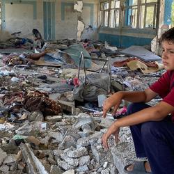 Boy sitting in the rubble of a destroyed UNRWA school in Nuseirat, Middle Areas, Gaza 2024